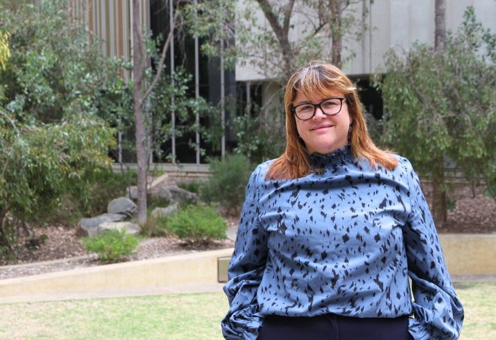 Nurse Unit Manager Clare Bradshaw standing in front of a courtyard, smiling.