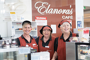 Three female volunteers stand beside the counter at Elanora's Cafe