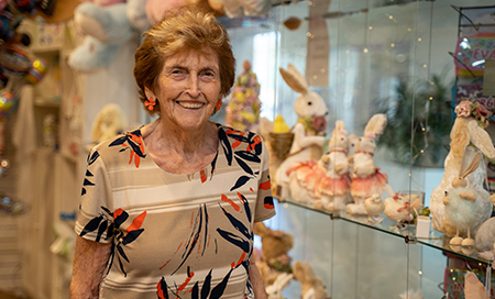 A woman stands besides shelves filled with soft toys and ornaments