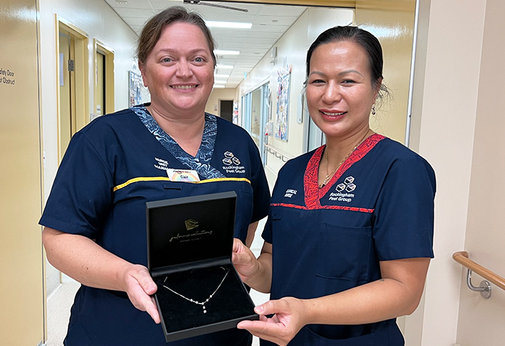 Two nurses holding a diamond necklace in felt case