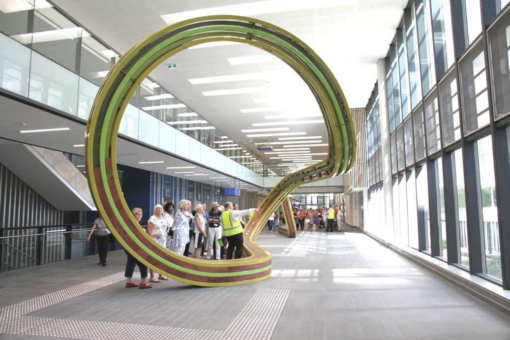 Visitors take a guided tour inside Fiona Stanley Hospital, stop to look at the art sculpture bench in the main concourse
