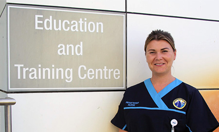 A female registered nurse stands beside a sign that reads Education and Training Centre