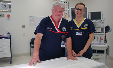 A male and female nurse stand in an operating theatre